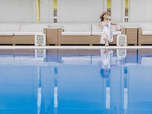 a woman sitting on a couch next to a swimming pool at Okinawa EXES Naha in Naha