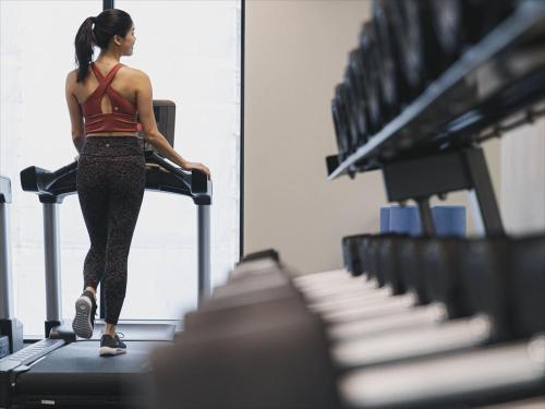 a woman walking on a treadmill in a gym at Okinawa EXES Naha in Naha