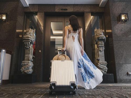 une femme en robe blanche tirant une valise dans l'établissement Okinawa EXES Naha, à Naha