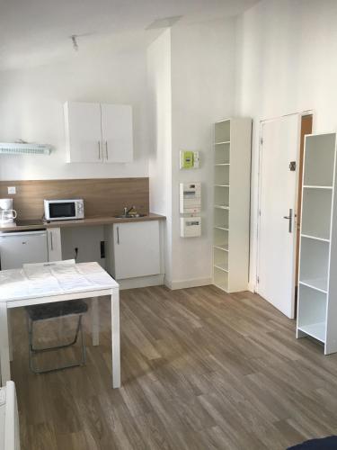 une cuisine avec des armoires blanches et une table blanche dans l'établissement Joli studio meublé très calme 15mn des plages et wifi gratuit, à Marseille