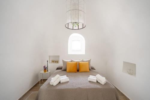 a white bedroom with a bed with yellow pillows at Trulli del Minareto in Selva di Fasano