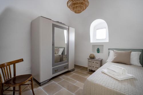a bedroom with a bed with a mirror and a chair at Trulli del Minareto in Selva di Fasano