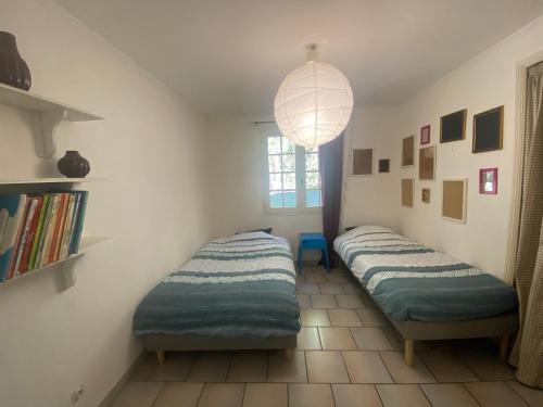 deux lits jumeaux dans une chambre avec fenêtre dans l'établissement Charmante Maison Piscine, à Pont-Saint-Esprit