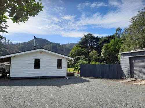 ein weißes Haus mit einer Garage und einem Zaun in der Unterkunft Akatarawa Valley Retreat a Cosy Two Bedroom Guest Suite in Upper Hutt