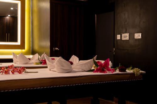 a bed with white pillows and red flowers on it at Viceroy Luxury Mountain Resort and Spa in Munnar