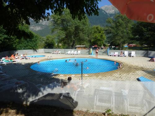 a swimming pool with people sitting in chairs around it at Camping, Hôtel De Plein Air Les Cariamas in Chateauroux-les-Alpes