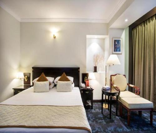 新德里的住宿－Hotel ALVAA GRAND Near Delhi Airport BY-AERO HOME STAY，配有一张床和一把椅子的酒店客房