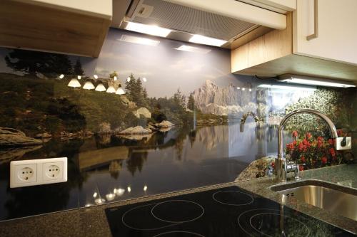 a kitchen with a painting of a river on the wall at Appartement Central by Schladmingurlaub in Schladming
