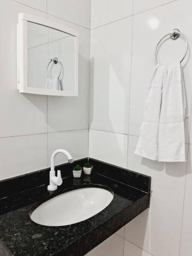 een witte badkamer met een wastafel en een handdoek bij Flat ideal para familia e grupos de amigos proximo ao aeroporto e rodoviária in Palmas