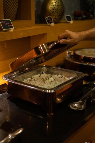 a person preparing food in a pan on a stove at Viceroy Luxury Mountain Resort and Spa in Munnar