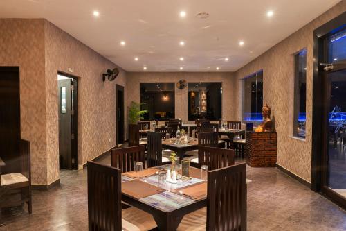 a restaurant with tables and chairs and a woman in the background at Viceroy Luxury Mountain Resort and Spa in Munnar