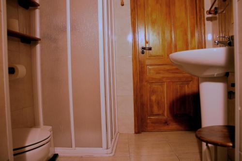 a bathroom with a toilet and a sink and a door at Casa Rural "La Bardena Blanca I " in Arguedas