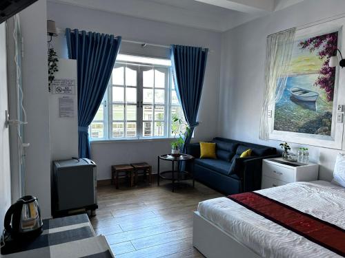 a bedroom with a bed and a couch and a window at The Blue House in Da Lat