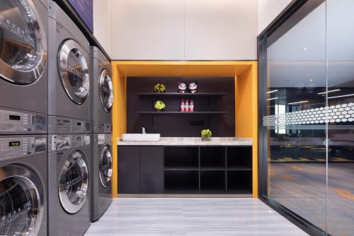 a laundry room with three washing machines and a sink at Hilton Hotel by Hampton Wuhan Zhongnan Street Branch in Wuhan