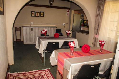 a room with two tables with red flowers on them at Ingwenya Guesthouse in Ermelo
