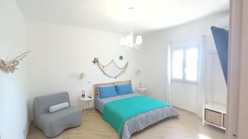 ein weißes Schlafzimmer mit einem Bett und einem Stuhl in der Unterkunft Villa Chimera in Pachino