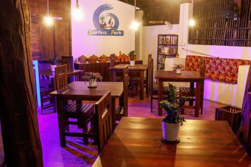 a restaurant with wooden tables and chairs with purple lights at Surfers Park Arugambay in Arugam Bay