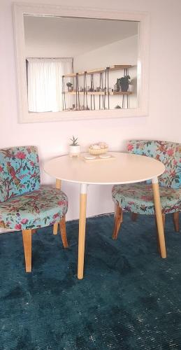 mesa blanca con 2 sillas, mesa y espejo en Primrose Seaside Healing Retreat, en Primrose Sands