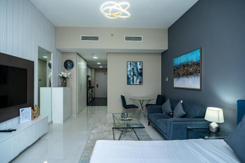 a living room with a blue couch and a tv at Escape24 Studio at Loreto with Community View in Dubai