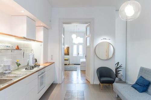 a white kitchen with a sink and a mirror at NewSunny Apartment at the BudaCastle in Budapest