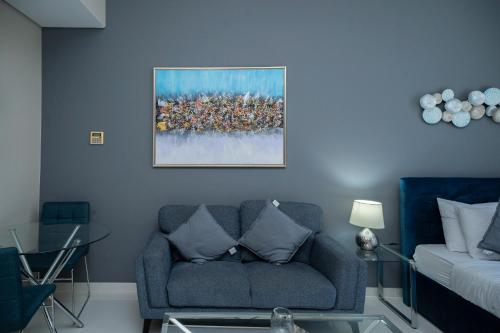 a living room with a couch and a painting on the wall at Escape24 Studio at Loreto with Community View in Dubai