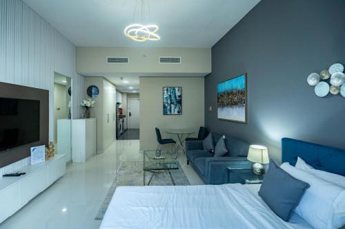 a bedroom with a blue bed and a living room at Escape24 Studio at Loreto with Community View in Dubai