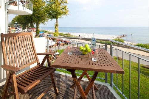 a wooden table and a chair on a balcony with the beach at Hof Sierksdorf in Sierksdorf