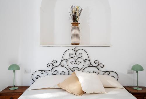 a white bedroom with a white bed with a vase on top at Villa Pineta - Holiday House in Anacapri