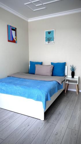 1 dormitorio con 1 cama grande con sábanas azules en Новая квартира с панорамным видом на горы en Almaty
