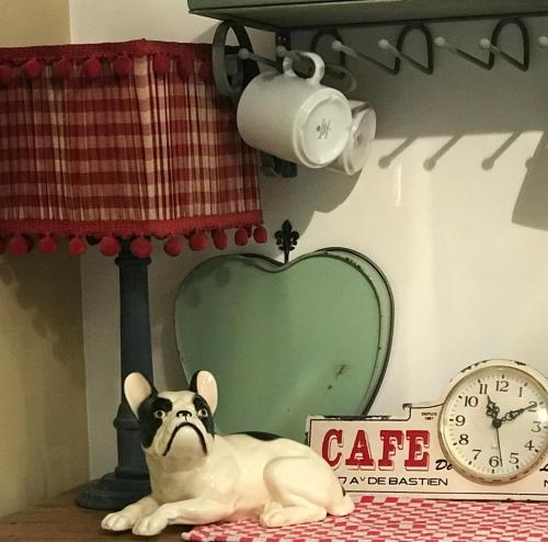 a dog laying on a table next to a clock at La Maison Ancienne Eymet in Eymet