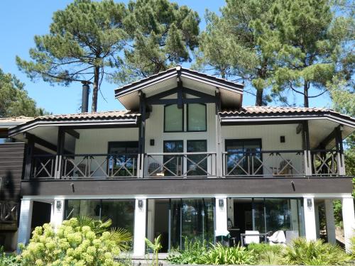 une grande maison avec un balcon et des arbres dans l'établissement Entre Océan et Lac, vue sur le golf, à Lacanau