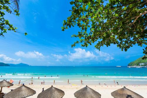 um grupo de pessoas em uma praia com o oceano em Sunshine Resort Intime Sanya em Sanya