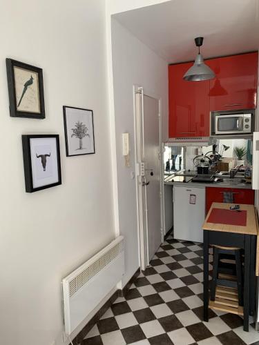 une cuisine avec des placards rouges et un sol en damier dans l'établissement Studio au cœur de la ville, à Nice