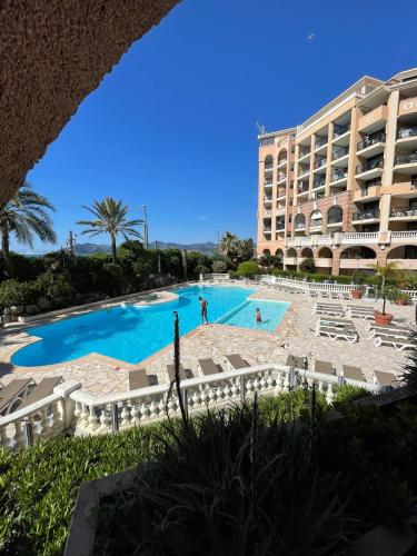 une grande piscine en face d'un grand bâtiment dans l'établissement Résidence Palme d'Azur Cannes La Bocca, à Cannes