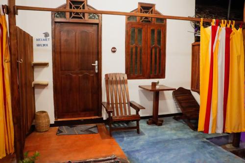 a room with wooden doors and a chair and a table at Surfers Park Arugambay in Arugam Bay