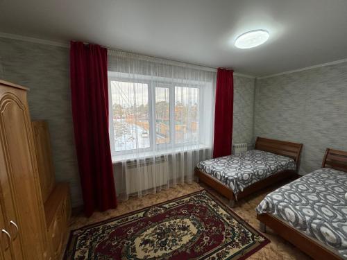 a bedroom with two beds and a window with red curtains at Квартира улица Абая 18 in Borovoye