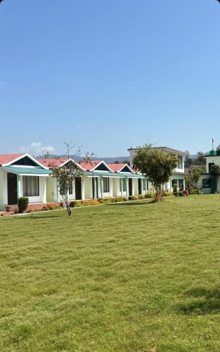 a group of houses in a yard with a green field at Rajaji Retreat in Rishīkesh