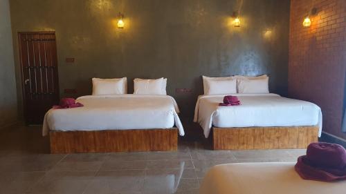 a bedroom with two beds with white sheets and purple towels at Ceylon Resort in Wilpattu