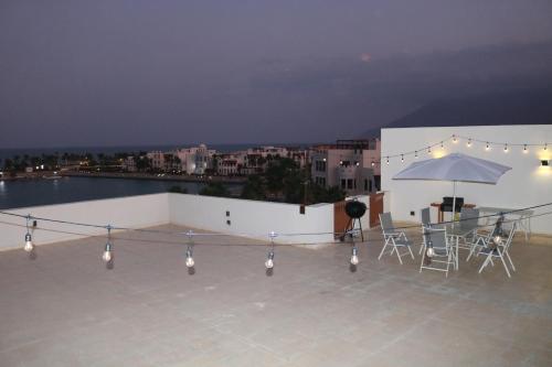 a rooftop patio with a table and an umbrella at Jabal Sifah Tha Marina View Apartment in Muscat