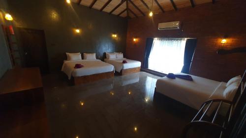 a room with two beds and a window with at Ceylon Resort in Wilpattu