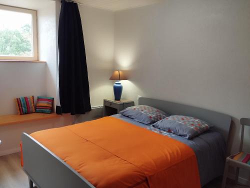 1 cama naranja en un dormitorio con ventana en Gite Le Lucimond, en Saint-André