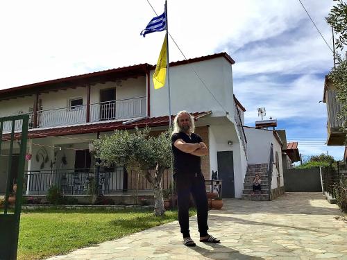 a man standing in front of a house with a flag at Apartment Antigoni in Nea Kalikratia