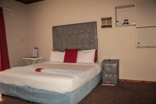 a bedroom with a large bed with a large headboard at Ingwenya Guesthouse in Ermelo