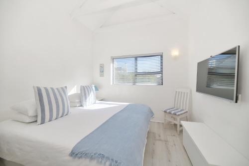 um quarto branco com uma cama grande e uma televisão em Owlet Cottage In Arniston em Arniston