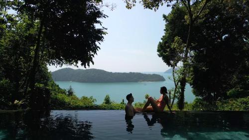 two people sitting in the water in a pool at Ambong Pool Villas - Private Pool in Pantai Cenang