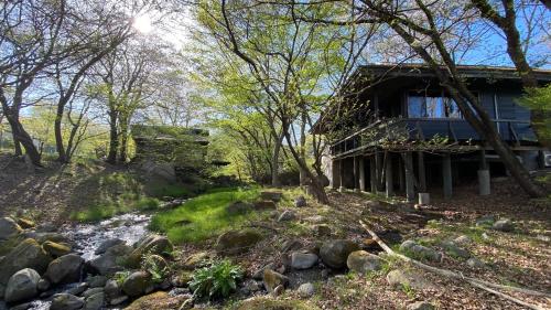 a cabin in the woods next to a stream at Tabinoteitaku Zao Miyagi in Zao