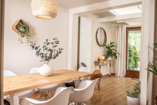 a dining room with a wooden table and white chairs at Belle maison lumineuse et paisible in Reims