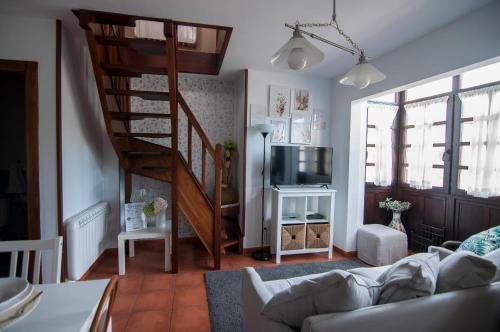 a living room with a spiral staircase and a television at La Casa de Maria in Santillana del Mar