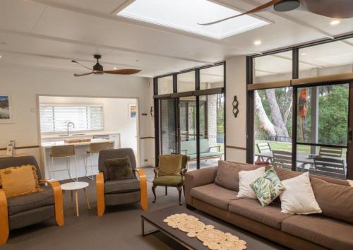a living room with a couch and chairs and a kitchen at Nelson's Oasis by the beach Apartment in Vincentia