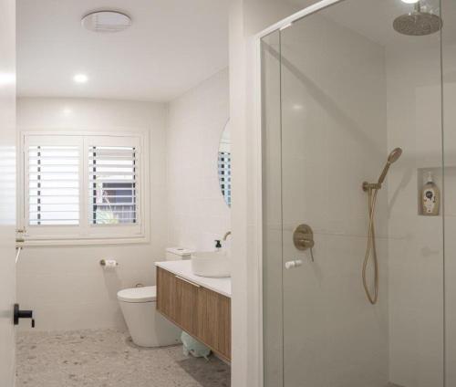 a bathroom with a shower and a toilet and a sink at Nelson's Oasis by the beach Apartment in Vincentia
